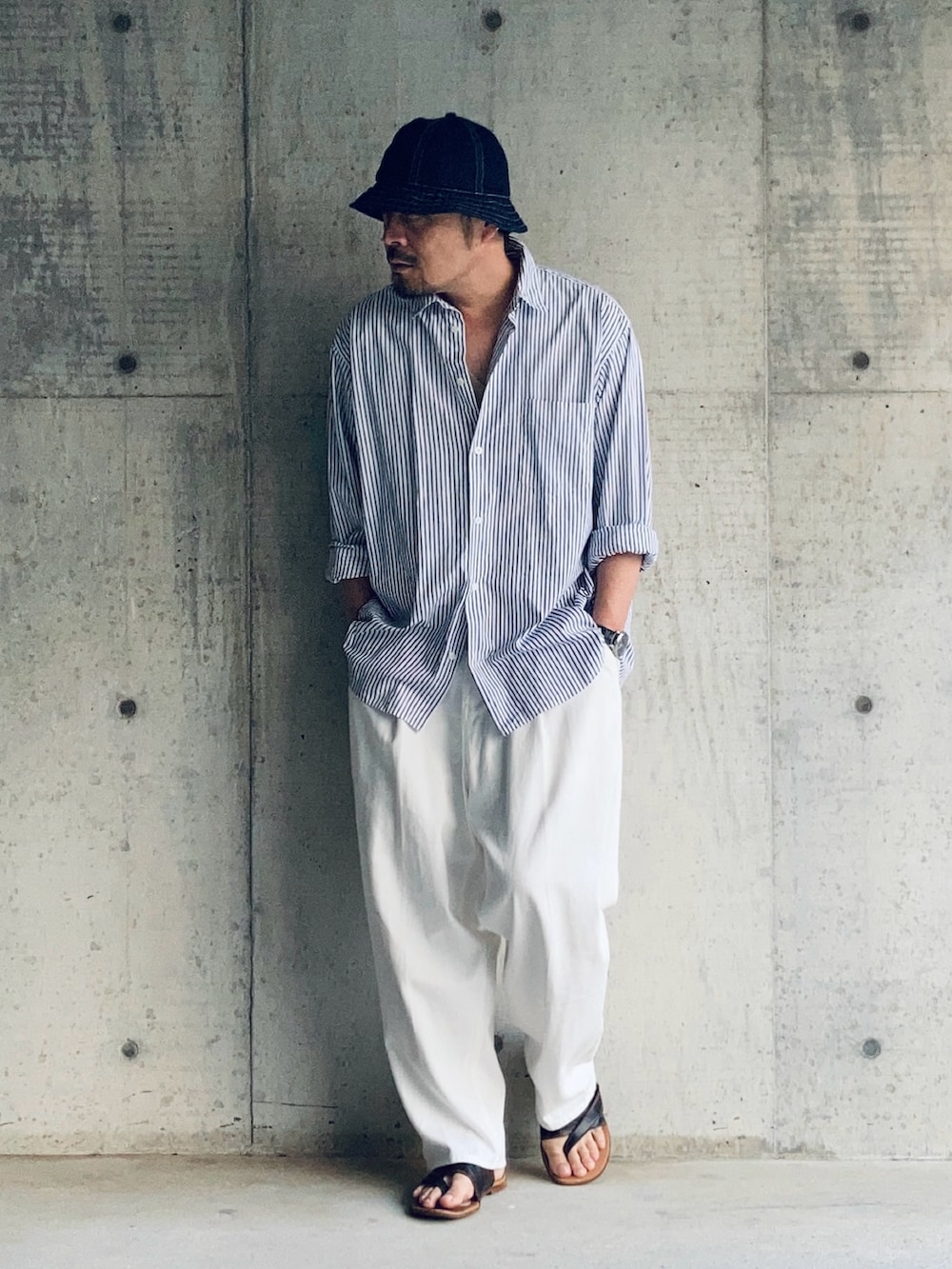 ホワイト系のスラックス、ブルー系のシャツ/ブラウス、ブラウン系のサンダルを着用したメンズの夏コーディネートの2枚目の写真