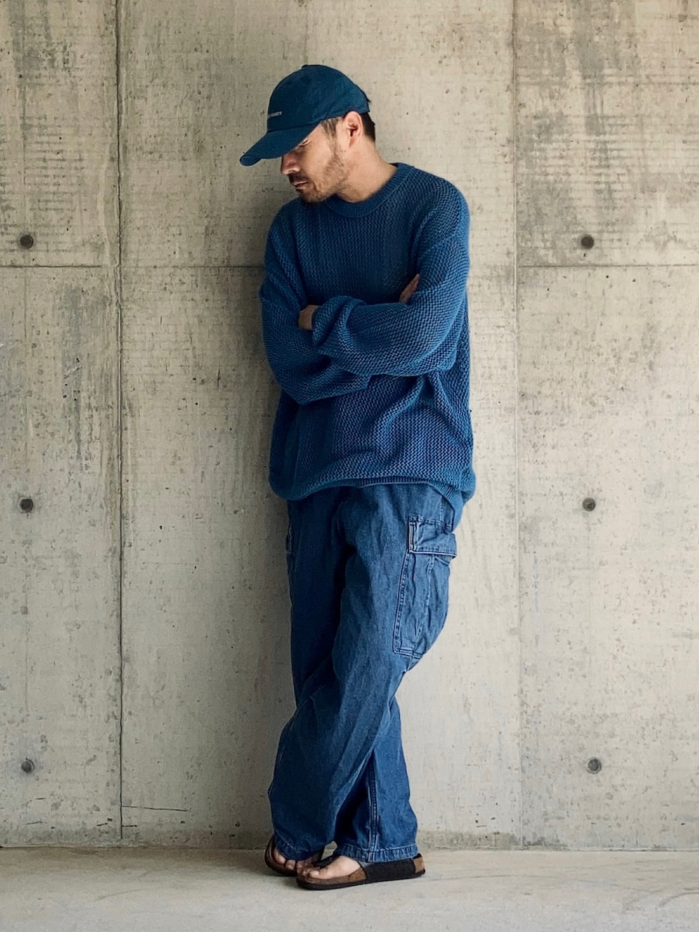 ブルー系のニット/セーター、ブルー系のカーゴパンツ、ブラック系のサンダルを着用したメンズの秋コーディネートの3枚目の写真