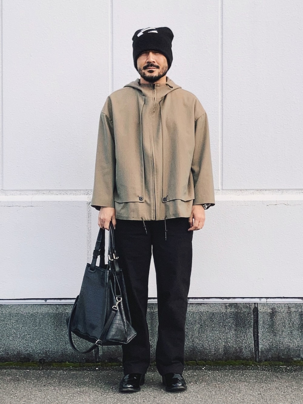 ベージュ系のブルゾン、ブラック系のパンツ、ブラック系のトートバッグを着用したメンズの秋コーディネートの2枚目の写真