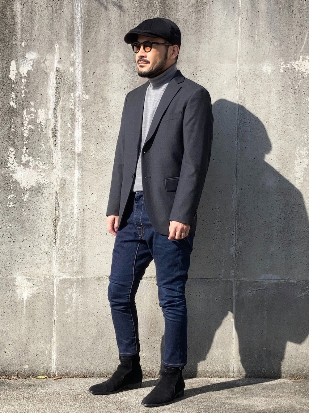 グレー系のテーラードジャケット、ブラック系のブーツ、ブルー系のデニムパンツを着用したメンズの秋コーディネートの3枚目の写真