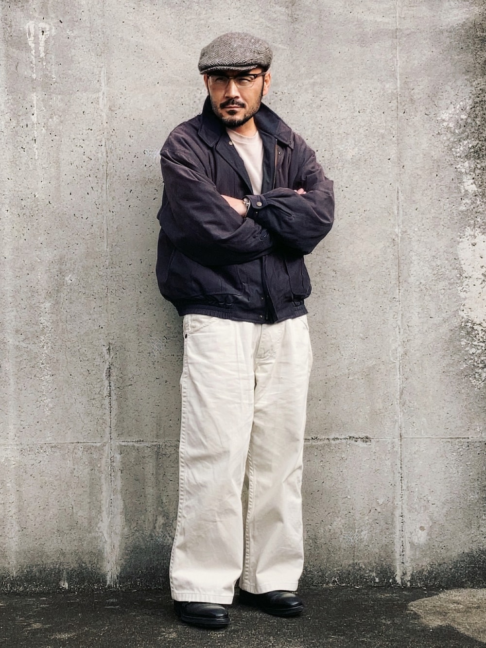 グレー系のブルゾン、ホワイト系のデニムパンツ、ブラック系のドレスシューズを着用したメンズの冬コーディネートの2枚目の写真