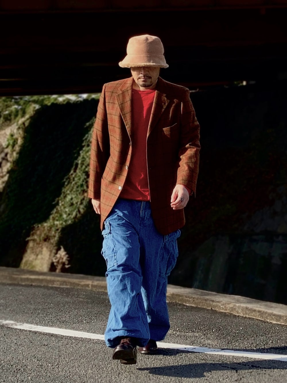 レッド系のニット/セーター、ブラウン系のテーラードジャケット、ブルー系のカーゴパンツを着用したメンズの冬コーディネートの2枚目の写真