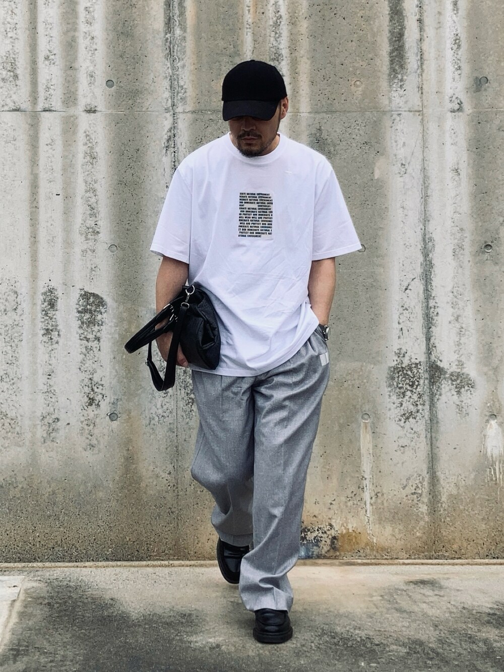 ホワイト系のTシャツ/カットソー、グレー系のスラックス、ブラック系のローファーを着用したメンズの春コーディネートの2枚目の写真