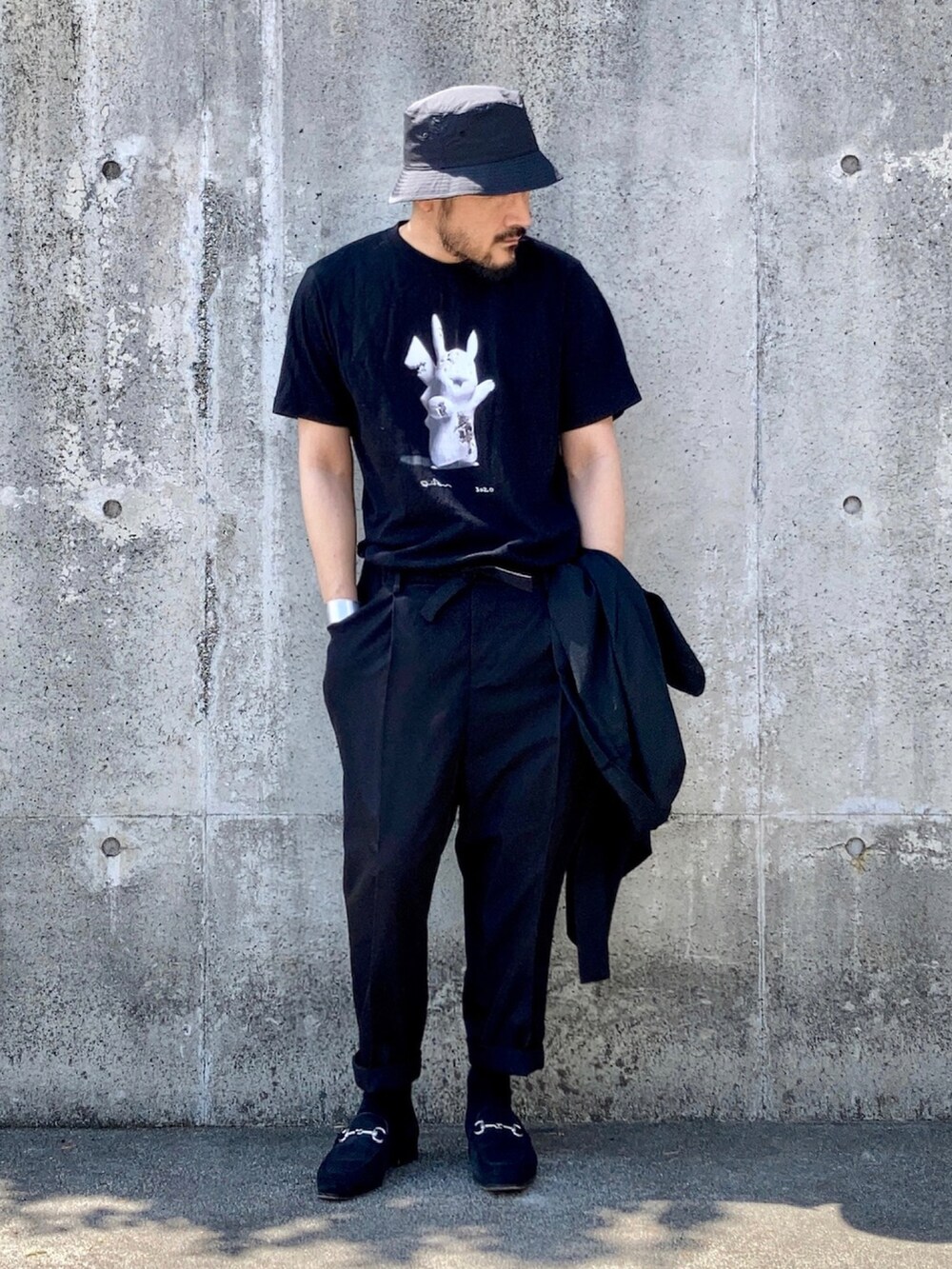 ブラック系のTシャツ/カットソー、ブラック系のスラックス、ブラック系のローファーを着用したメンズの秋コーディネートの4枚目の写真