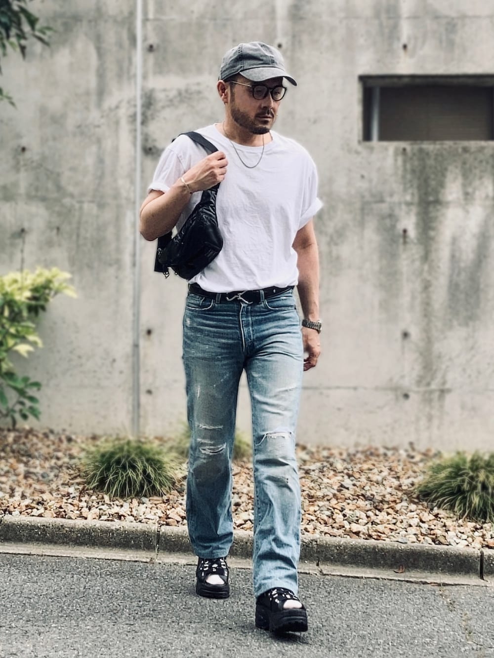 ホワイト系のTシャツ/カットソー、ブルー系のデニムパンツ、ブラック系のサンダルを着用したメンズの夏コーディネートの3枚目の写真