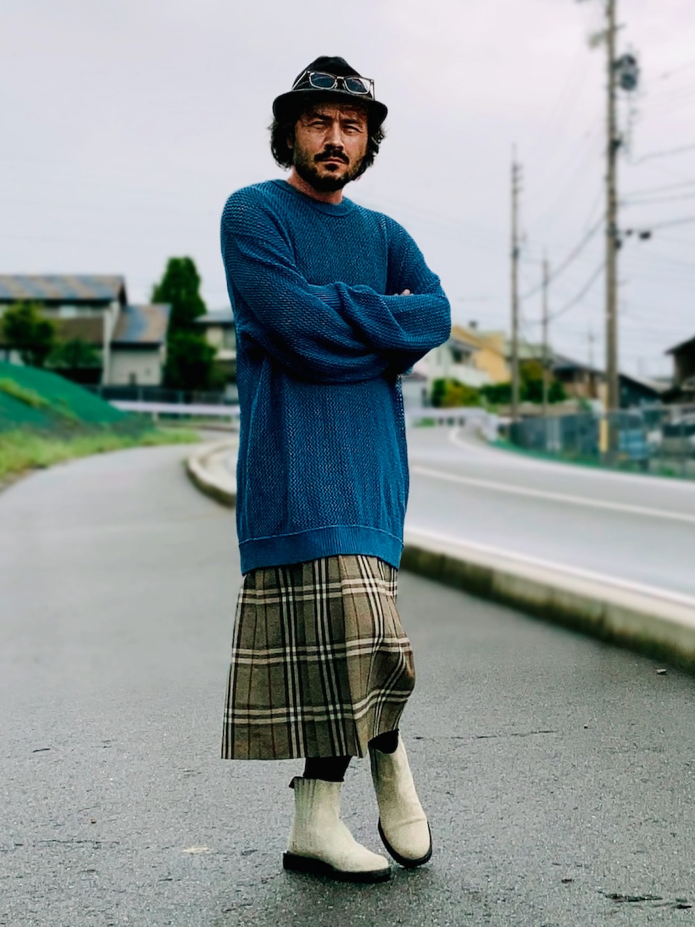 グレー系のスカート、ブルー系のニット/セーター、ベージュ系のブーツを着用したメンズの秋コーディネートの2枚目の写真