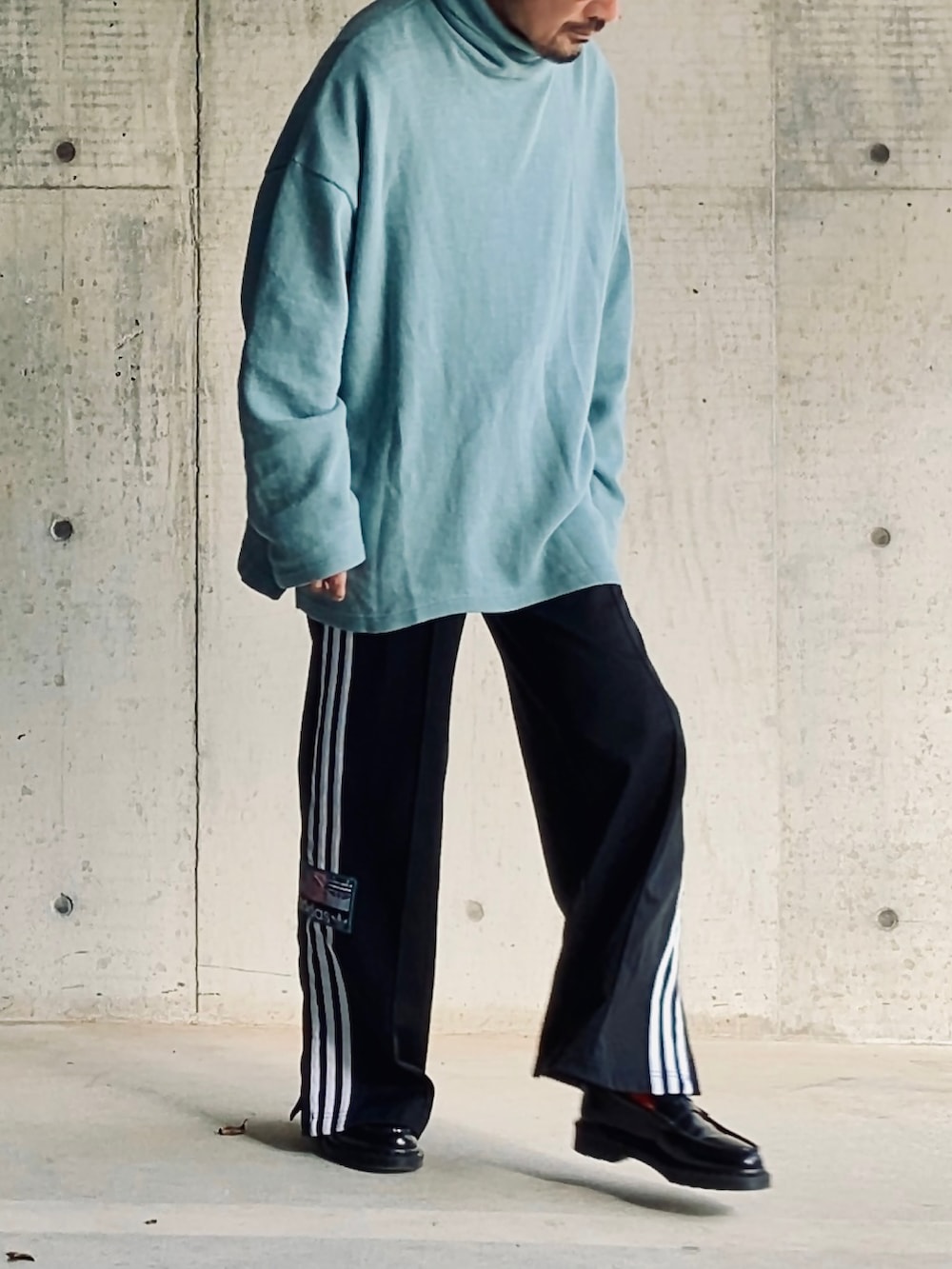 ブルー系のニット/セーター、ブラック系のスウェットパンツ、ブラック系のローファーを着用したメンズの秋コーディネートの3枚目の写真