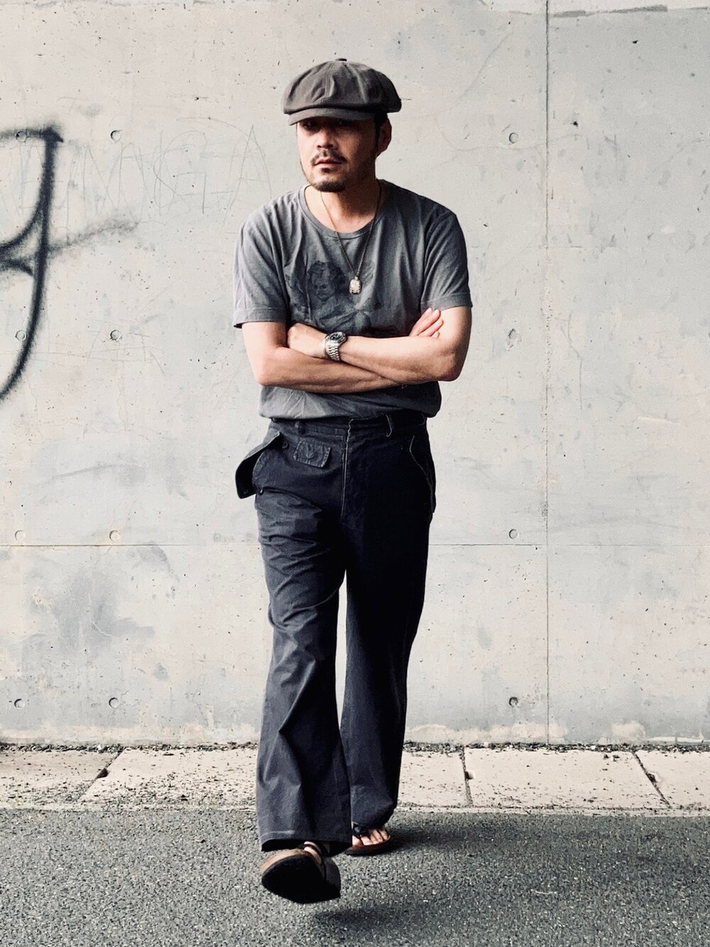 グレー系のTシャツ/カットソー、グレー系のスラックス、ブラック系のサンダルを着用したメンズの夏コーディネートの4枚目の写真