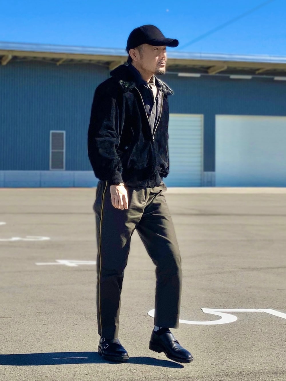 ブラック系のポロシャツ、ブラック系のブルゾン、グリーン系のスラックスを着用したメンズの秋コーディネートの2枚目の写真