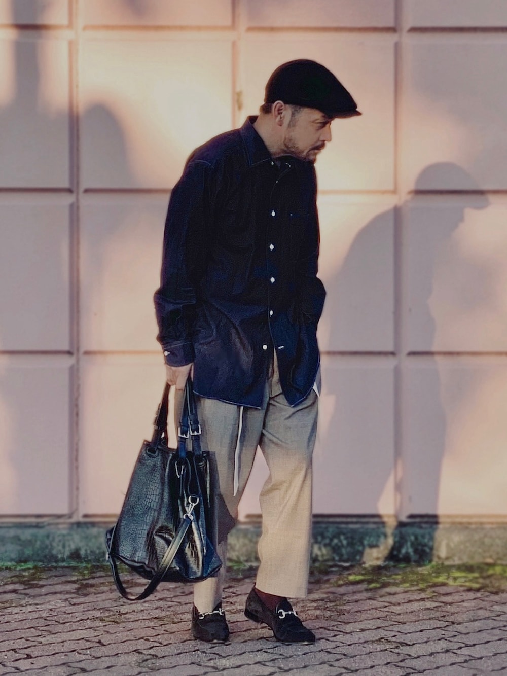 ブラウン系のスラックス、ブラック系のローファー、ブラック系のトートバッグを着用したメンズの秋コーディネートの3枚目の写真