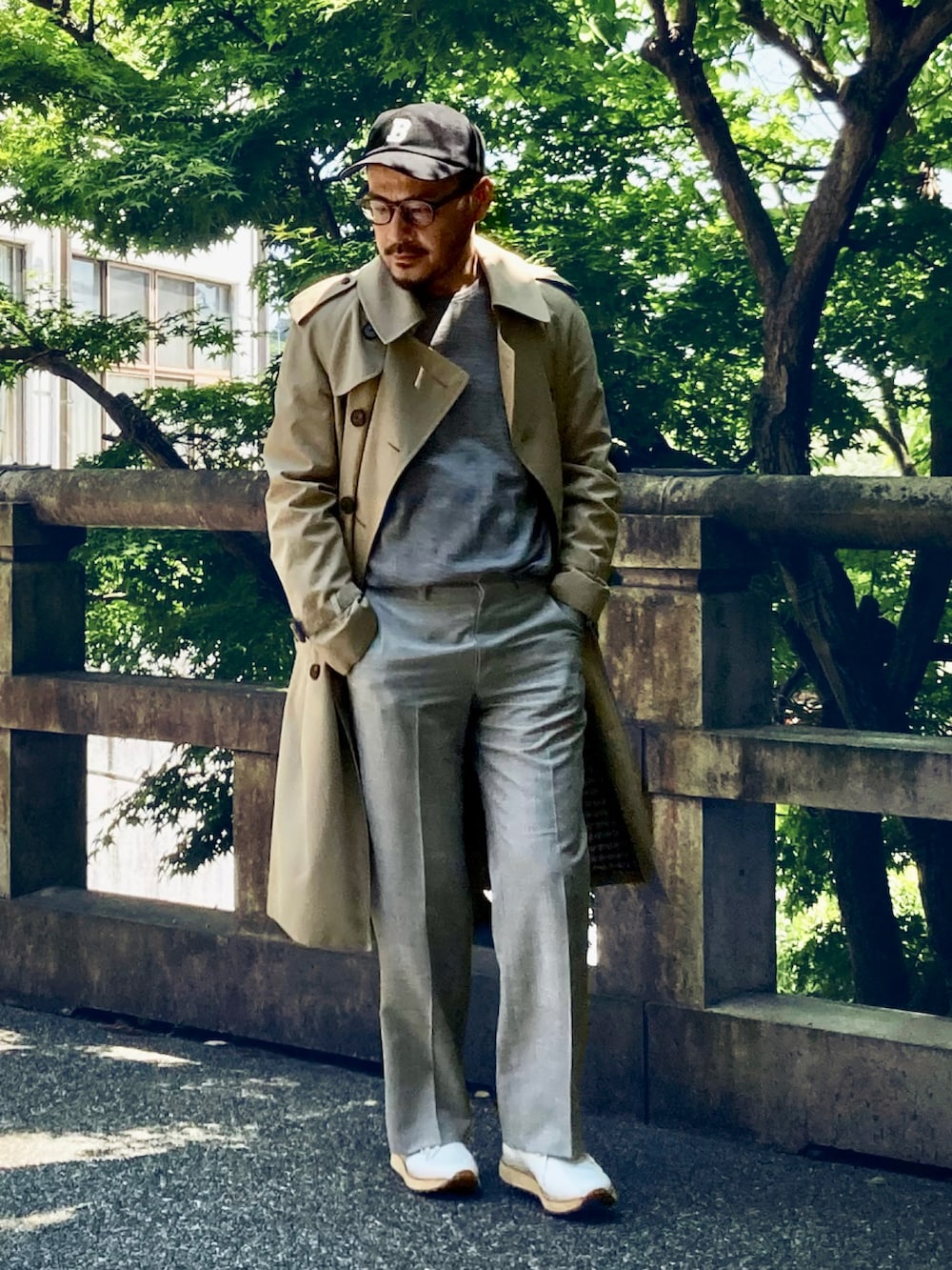 グレー系のニット/セーター、ベージュ系のトレンチコート、グレー系のスラックスを着用したメンズの春コーディネートの4枚目の写真