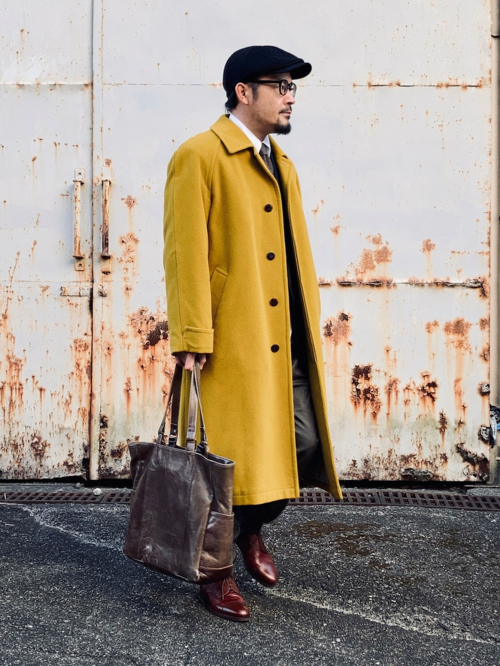 イエロー系のステンカラーコート、グリーン系のその他パンツ、ブラウン系のドレスシューズを着用したメンズの冬コーディネートの4枚目の写真