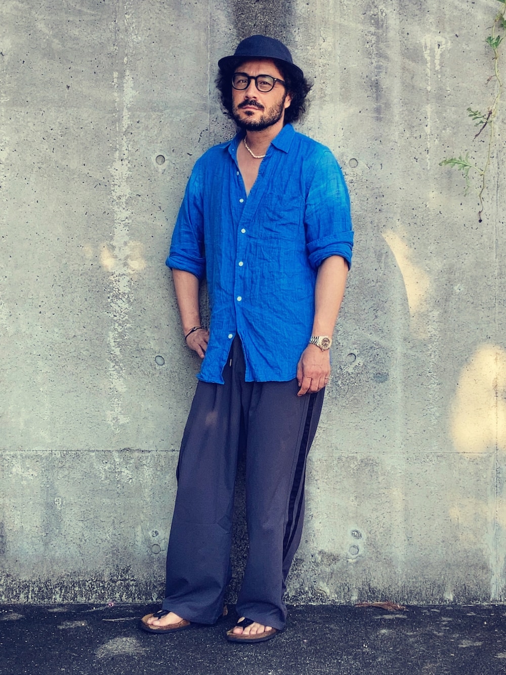 ブルー系のシャツ/ブラウス、グレー系のスラックス、ブラック系のサンダルを着用したメンズの夏コーディネートの3枚目の写真