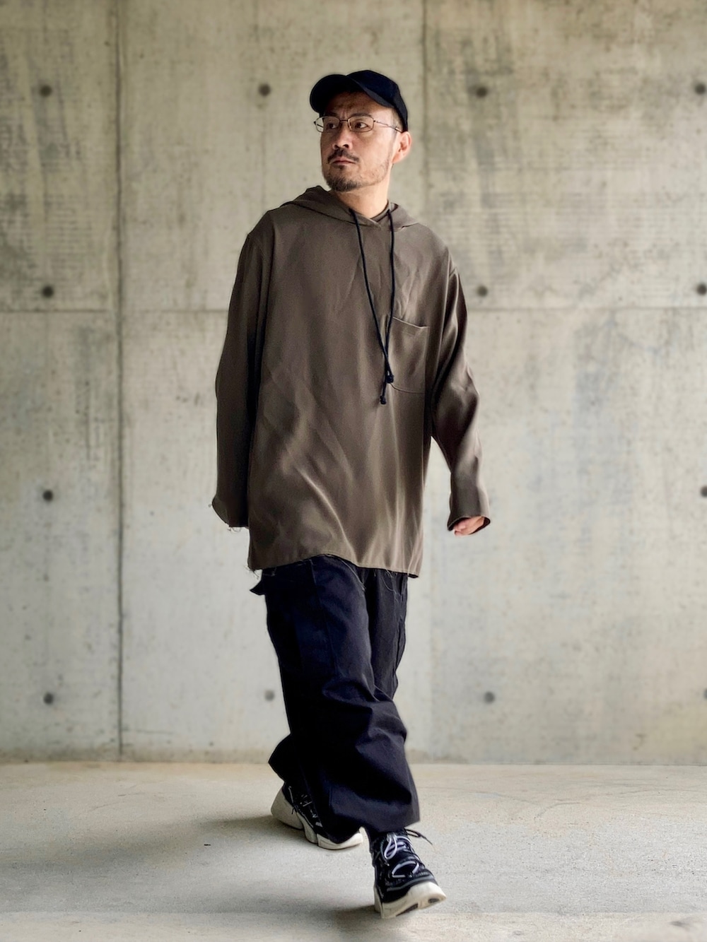 グレー系のパーカー、ブラック系のカーゴパンツ、ブラック系のスニーカーを着用したメンズの秋コーディネートの2枚目の写真