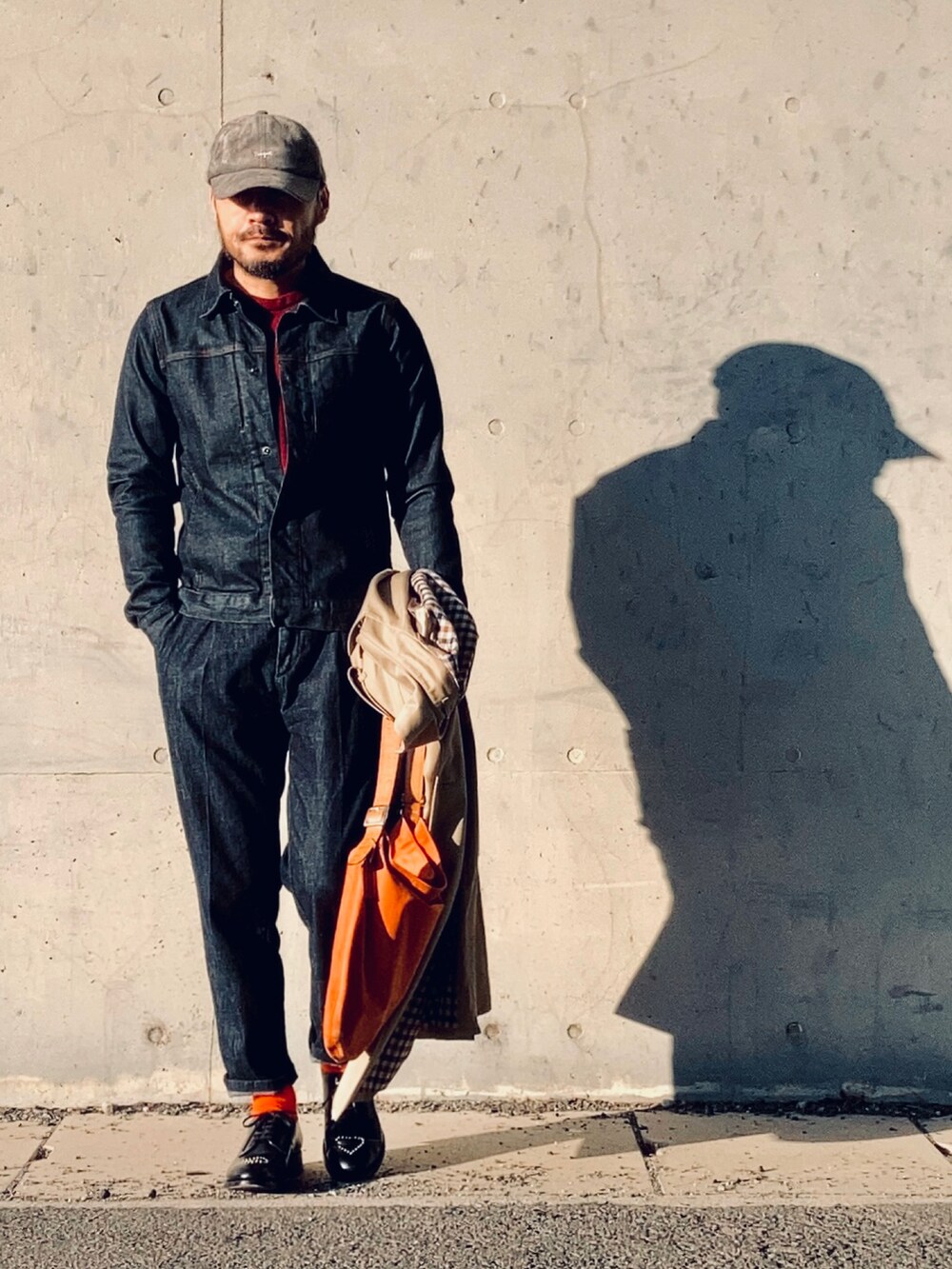 レッド系のニット/セーター、ブルー系のデニムジャケット、ベージュ系のトレンチコートを着用したメンズの冬コーディネートの3枚目の写真