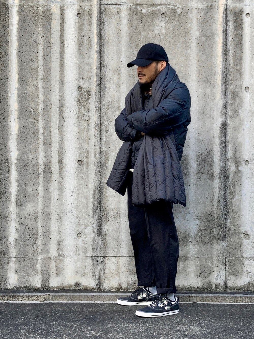 ベージュ系のTシャツ/カットソー、ブラック系のダウンジャケット/コート、ブラック系のスラックスを着用したメンズの冬コーディネートの2枚目の写真