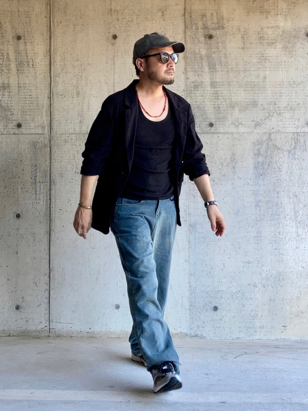 ブラック系のタンクトップ、ブラック系のテーラードジャケット、ブルー系のデニムパンツを着用したメンズの夏コーディネートの3枚目の写真