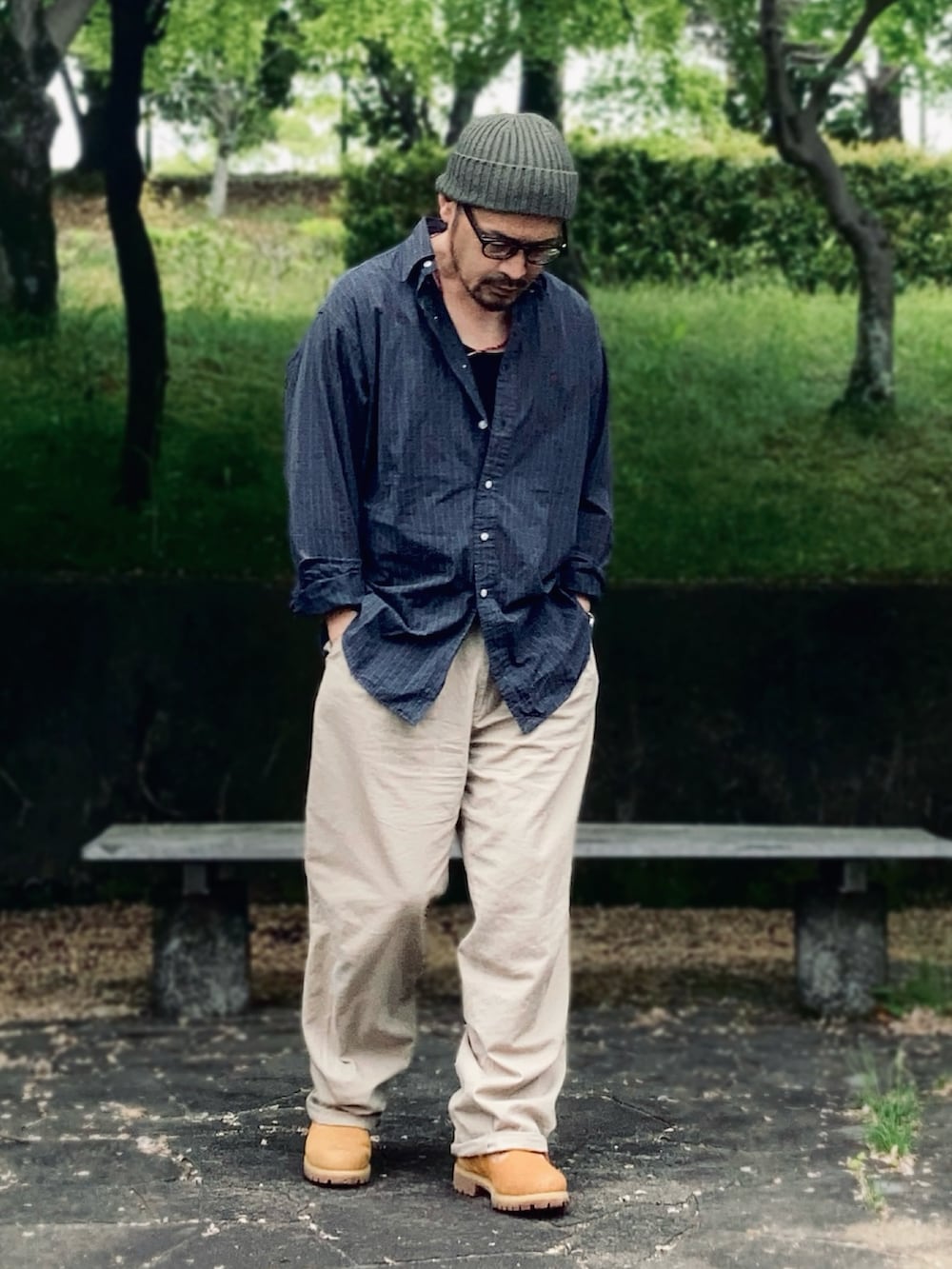 グリーン系のシャツ/ブラウス、ベージュ系のスラックス、イエロー系のブーツを着用したメンズの春コーディネートの2枚目の写真