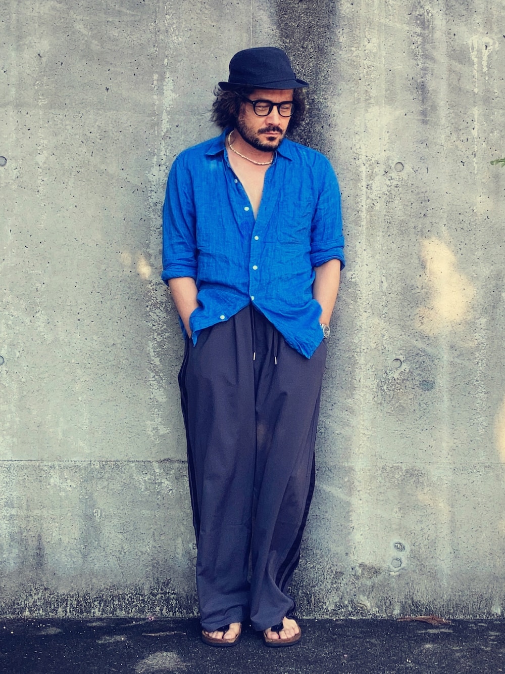 ブルー系のシャツ/ブラウス、グレー系のスラックス、ブラック系のサンダルを着用したメンズの夏コーディネートの2枚目の写真