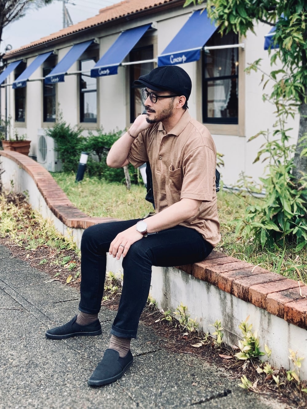 ブラック系のデニムパンツ、ブラック系のスリッポン、ブラック系のトートバッグを着用したメンズの春コーディネートの3枚目の写真