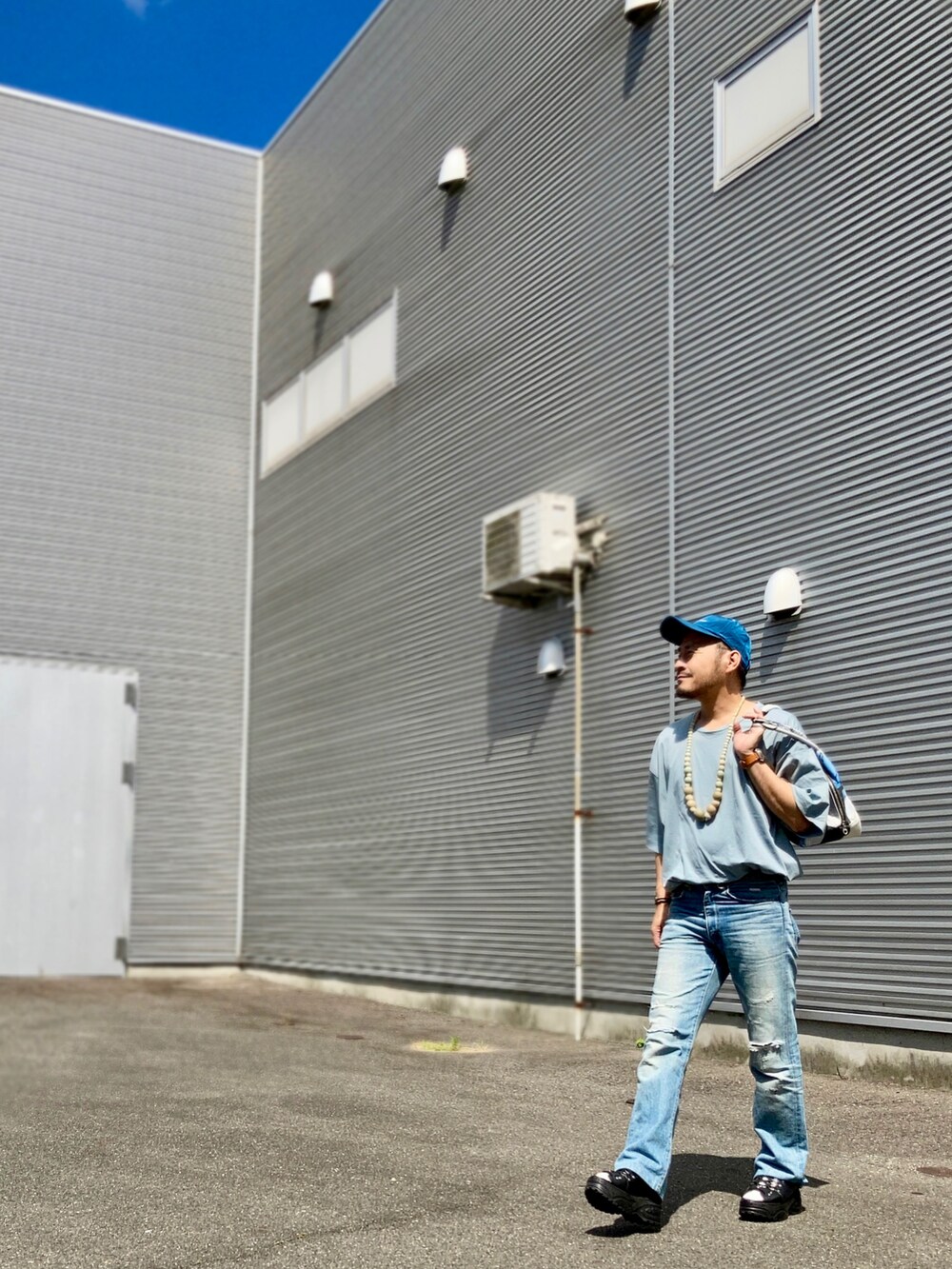 グリーン系のTシャツ/カットソー、ブルー系のデニムパンツ、ブラック系のサンダルを着用したメンズの夏コーディネートの3枚目の写真