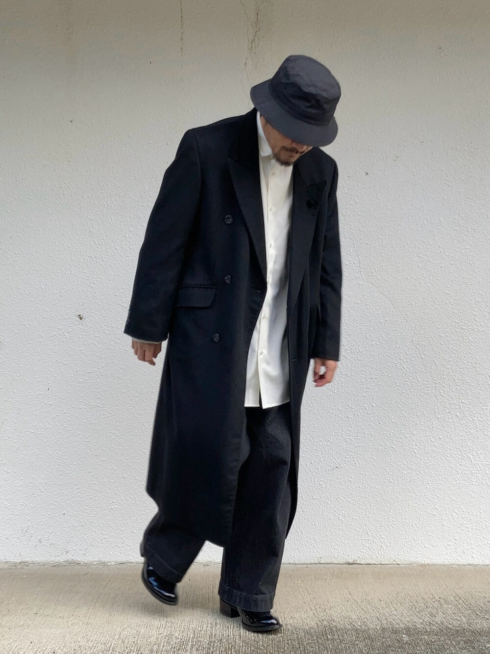 ホワイト系のシャツ/ブラウス、ブラック系のチェスターコート、ブラック系のデニムパンツを着用したメンズの冬コーディネートの4枚目の写真