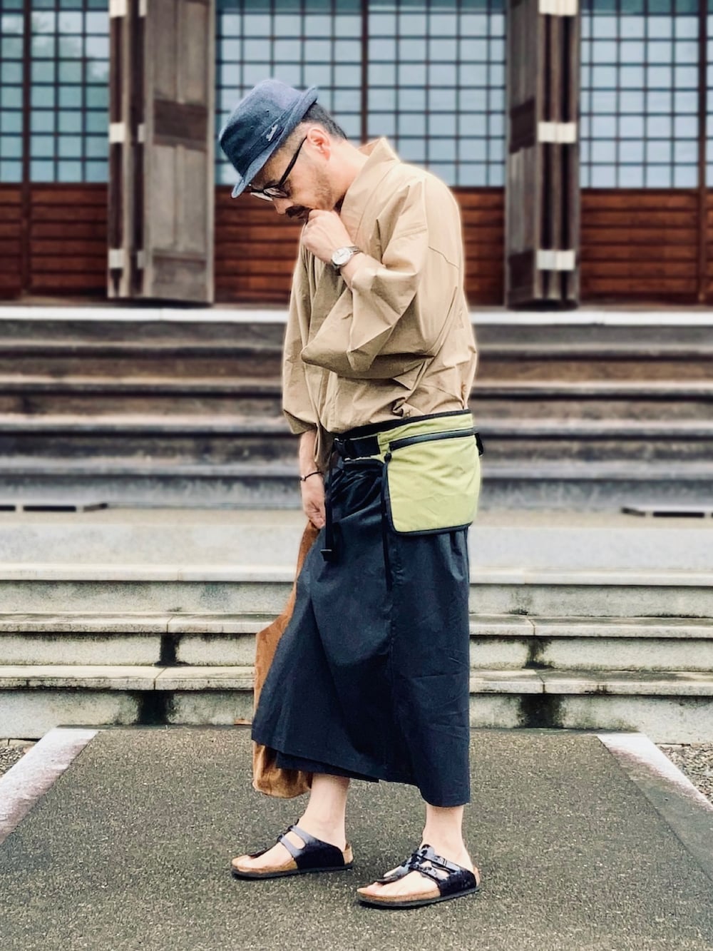 ブラック系のサンダル、イエロー系のボディバッグ/ウエストポーチ、ブラウン系のトートバッグを着用したメンズの夏コーディネートの2枚目の写真