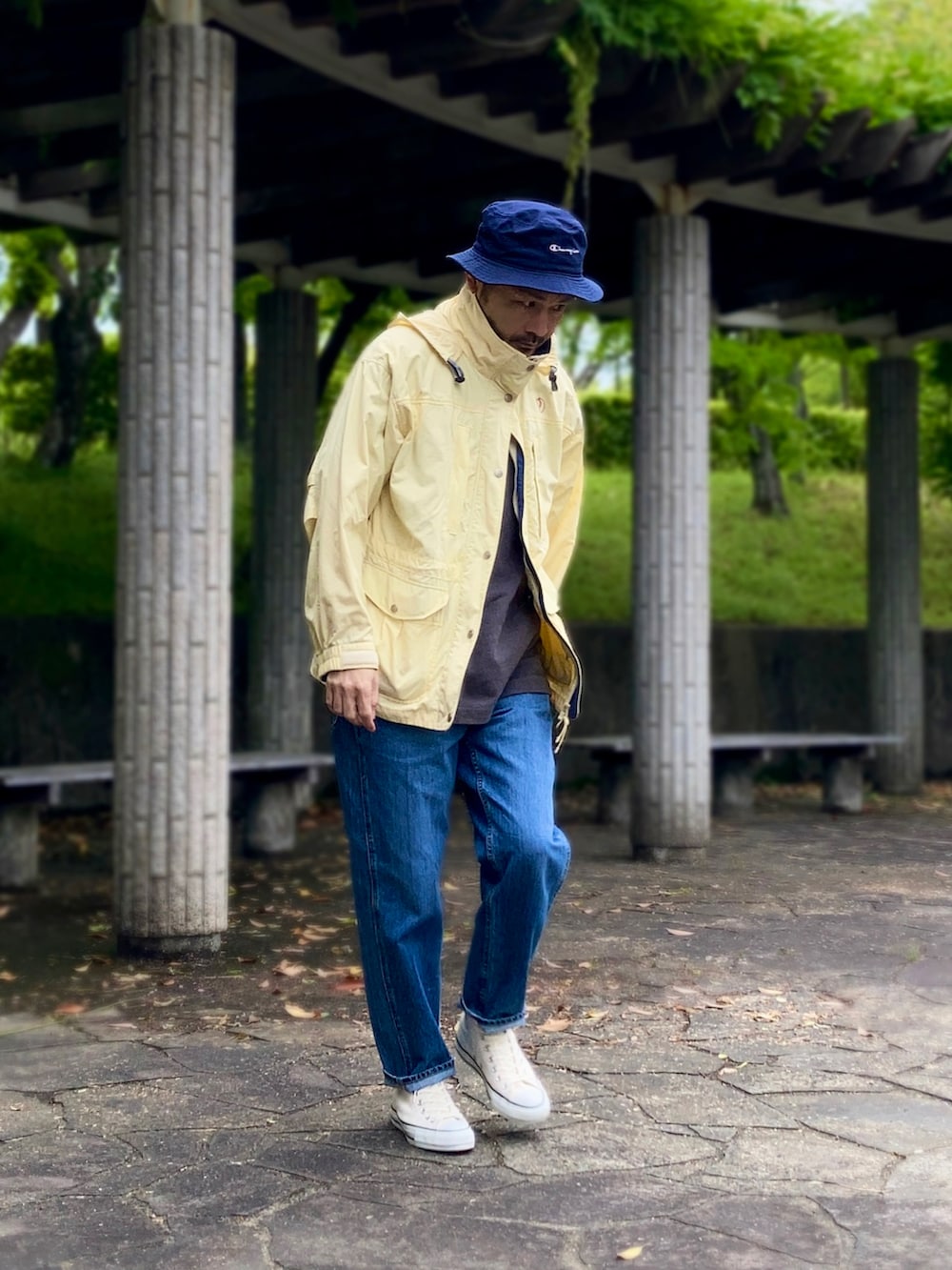 グレー系のポロシャツ、イエロー系のマウンテンパーカー、ブルー系のデニムパンツを着用したメンズの春コーディネートの3枚目の写真