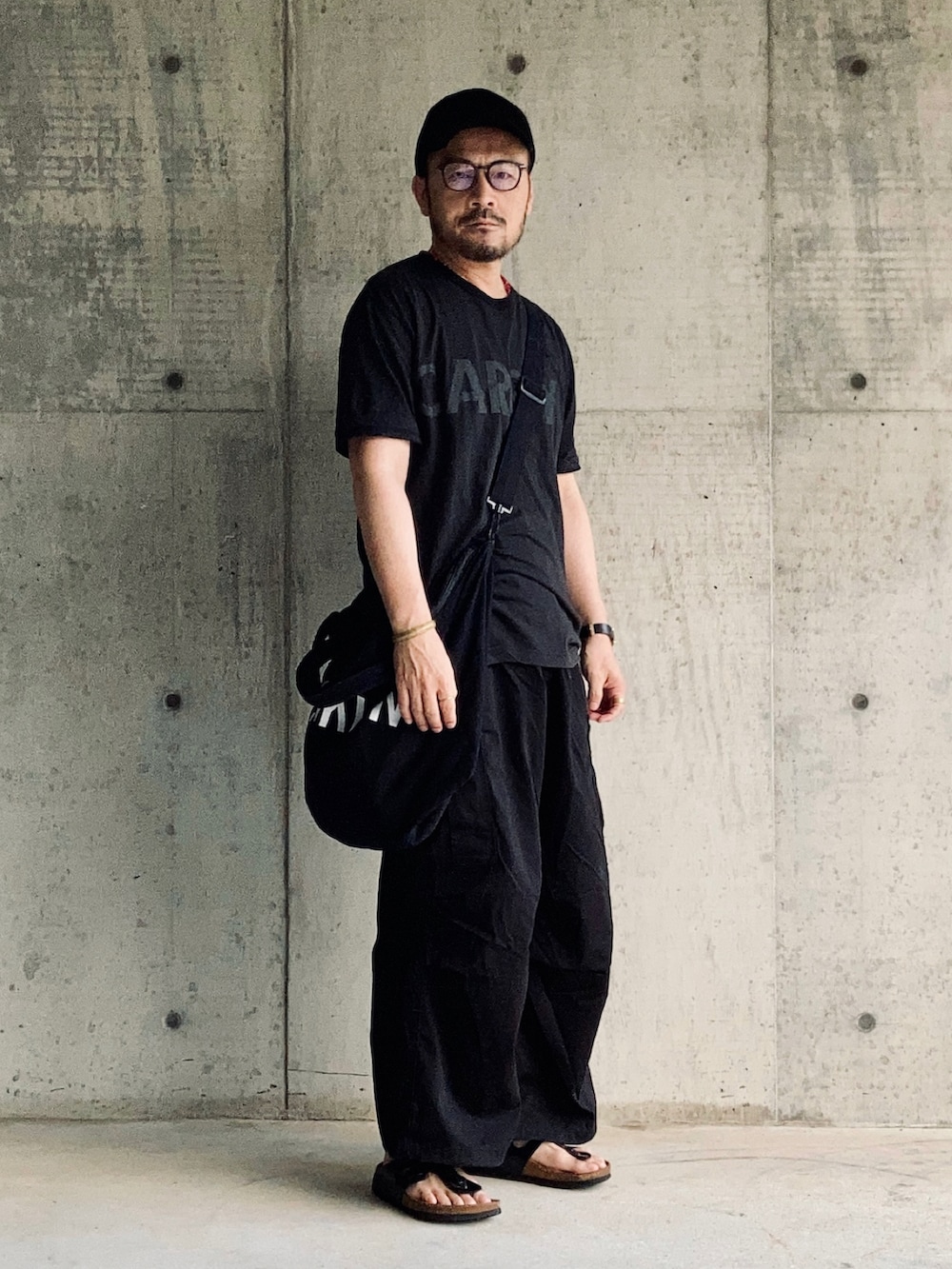 ブラック系のTシャツ/カットソー、ブラック系のカーゴパンツ、ブラック系のサンダルを着用したメンズの夏コーディネートの2枚目の写真