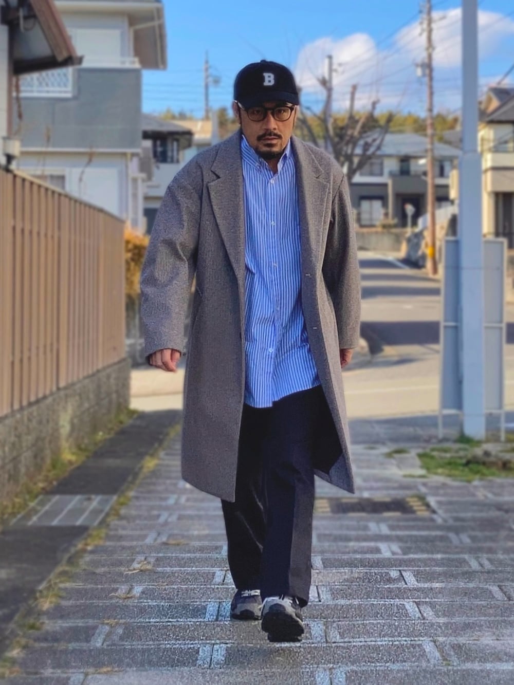グレー系のチェスターコート、ブルー系のシャツ/ブラウス、ブルー系のチノパンツを着用したメンズの冬コーディネートの4枚目の写真