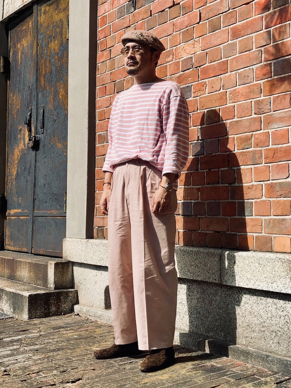 ピンク系のTシャツ/カットソー、ピンク系のスラックス、ブラウン系のスリッポンを着用したメンズの秋コーディネートの2枚目の写真