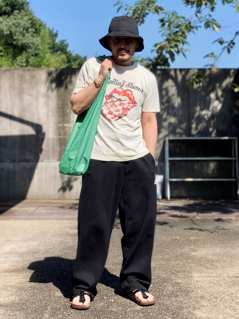 イエロー系のTシャツ/カットソー、ブラック系のパンツ、ブラック系のサンダルを着用したメンズの夏コーディネートの2枚目の写真