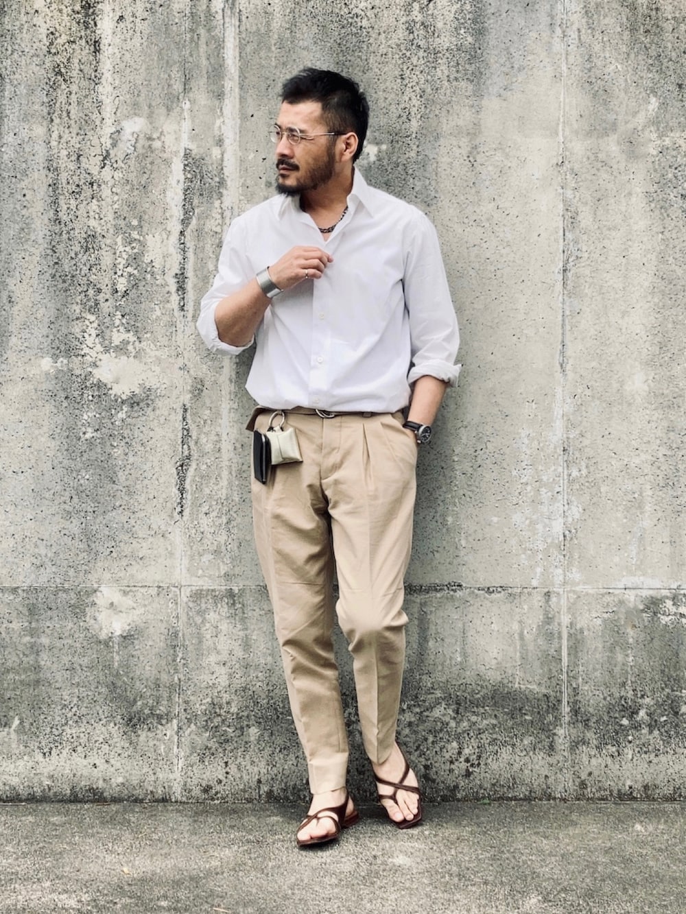 ベージュ系のスラックス、ブラウン系のサンダル、ブラック系のアナログ腕時計を着用したメンズの春コーディネートの2枚目の写真