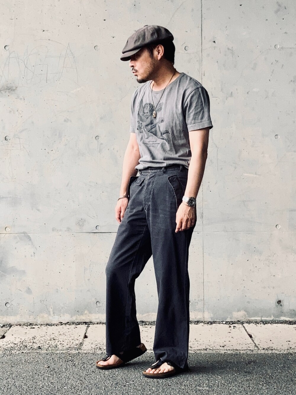 グレー系のTシャツ/カットソー、グレー系のスラックス、ブラック系のサンダルを着用したメンズの夏コーディネートの2枚目の写真