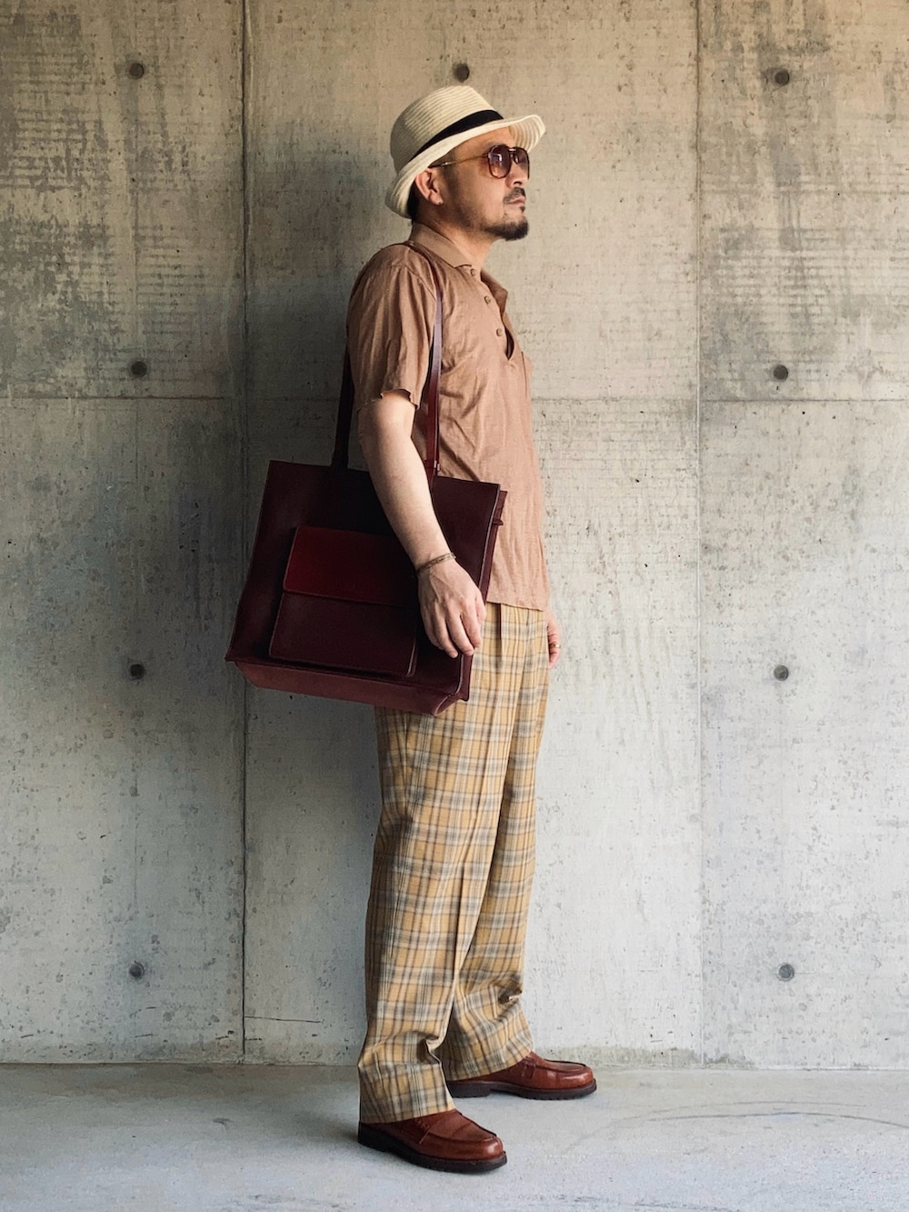 ブラウン系のローファー、ブラウン系のポロシャツ、イエロー系のスラックスを着用したメンズの春コーディネートの3枚目の写真