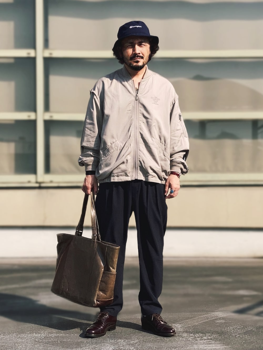 ベージュ系のMA-1、ブルー系のスラックス、レッド系のドレスシューズを着用したメンズの春コーディネートの2枚目の写真