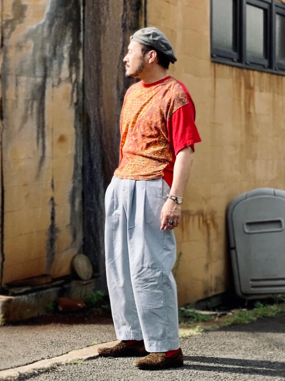 レッド系のTシャツ/カットソー、グレー系のパンツ、ブラウン系のスリッポンを着用したメンズの夏コーディネートの3枚目の写真