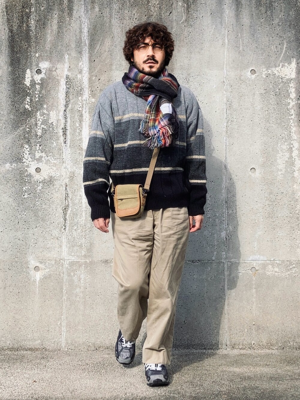 グレー系のニット/セーター、ベージュ系のチノパンツ、ブラック系のスニーカーを着用したメンズの冬コーディネートの3枚目の写真