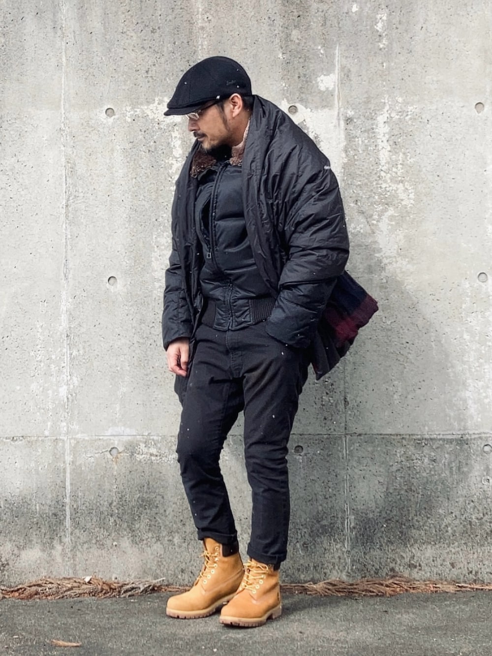 ブラック系のダウンジャケット/コート、ブラック系のデニムパンツ、イエロー系のブーツを着用したメンズの冬コーディネートの3枚目の写真