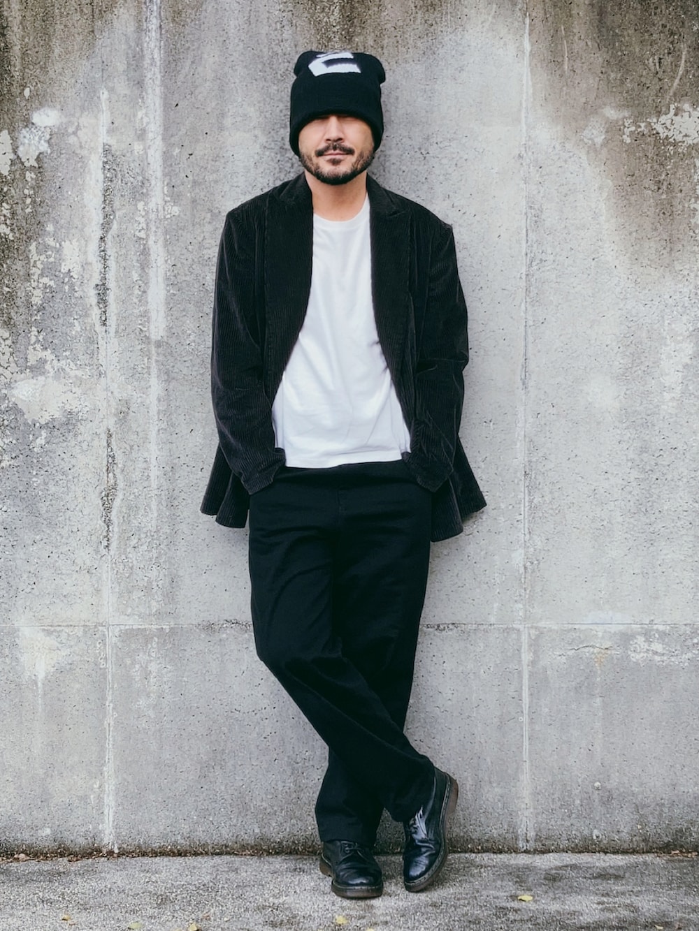 グレー系のテーラードジャケット、ブラック系のパンツ、ブラック系のブーツを着用したメンズの秋コーディネートの3枚目の写真