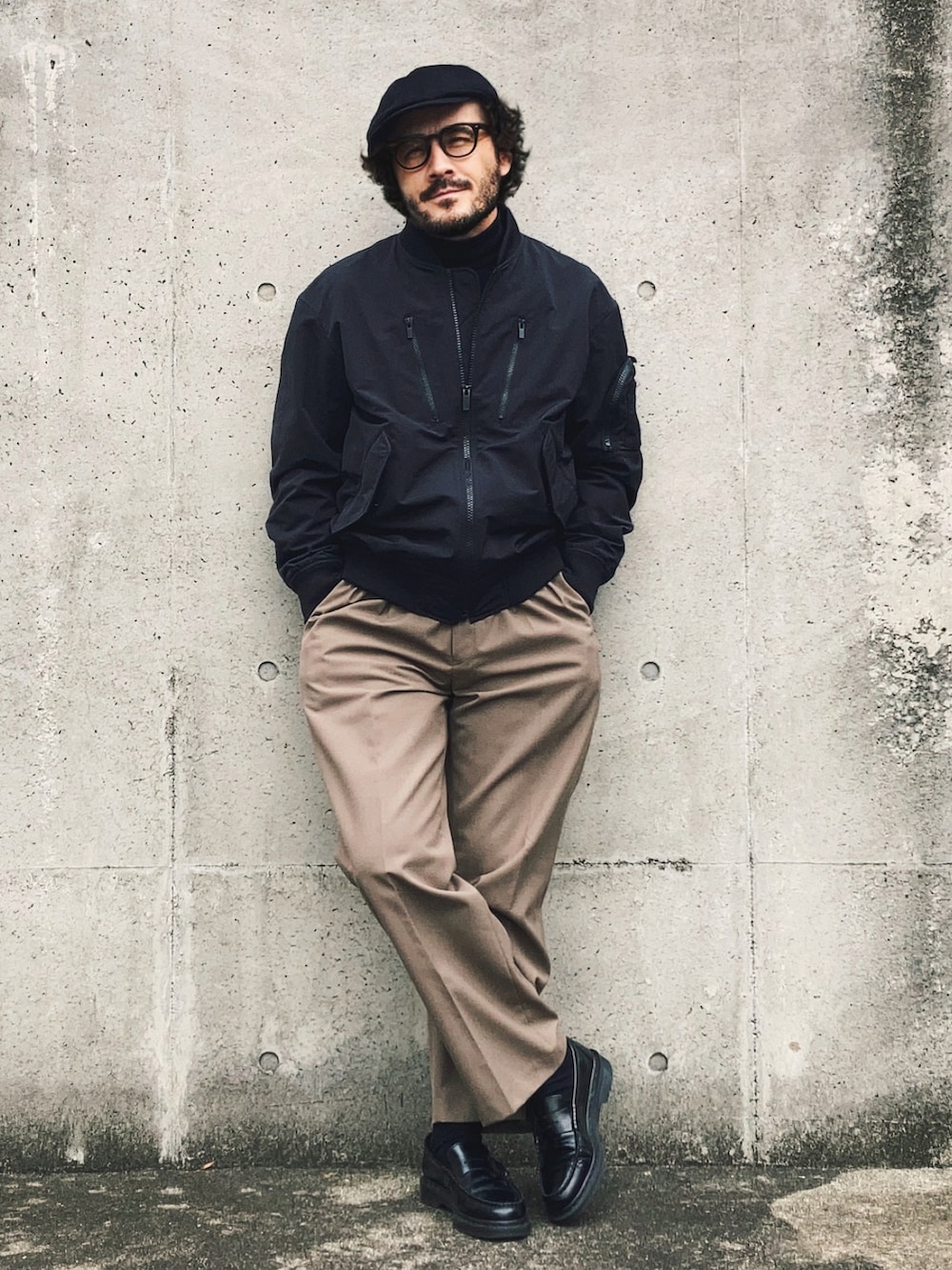 ブラック系のMA-1、ブラック系のニット/セーター、ベージュ系のスラックスを着用したメンズの春コーディネートの3枚目の写真