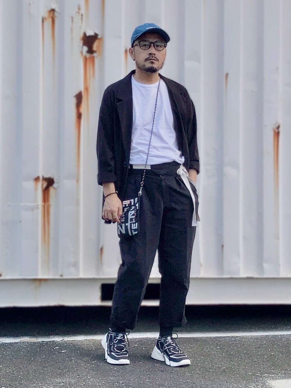 ホワイト系のTシャツ/カットソー、ブラック系のテーラードジャケット、ブラック系のその他パンツを着用したメンズの夏コーディネートの2枚目の写真