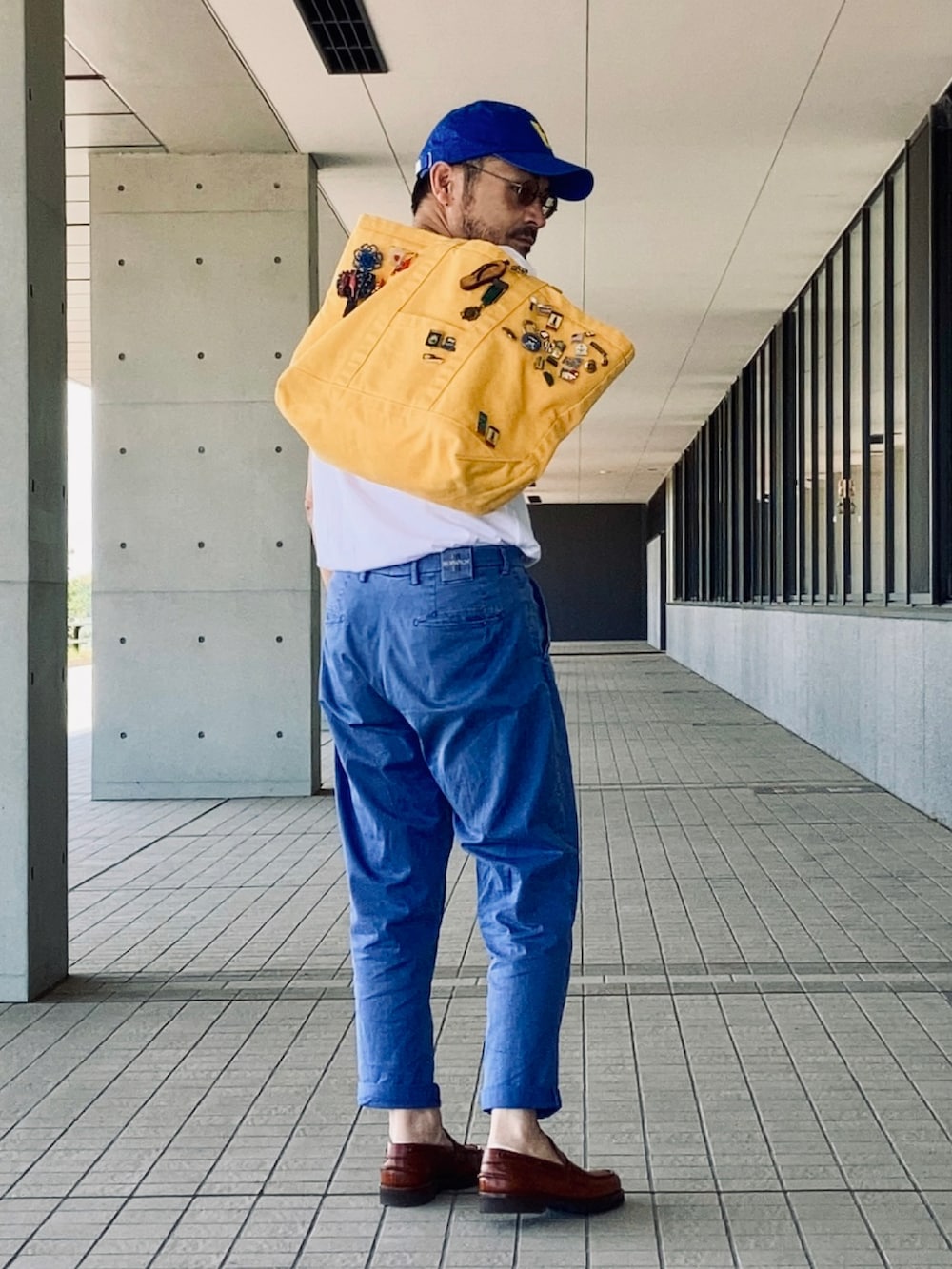 ホワイト系のTシャツ/カットソー、ブルー系のスラックス、ブラウン系のローファーを着用したメンズの夏コーディネートの3枚目の写真