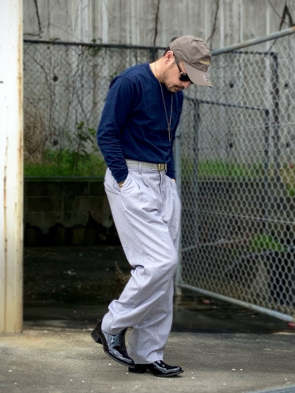 グレー系のスラックス、ブラック系のブーツ、グレー系のキャップを着用したメンズの春コーディネートの3枚目の写真