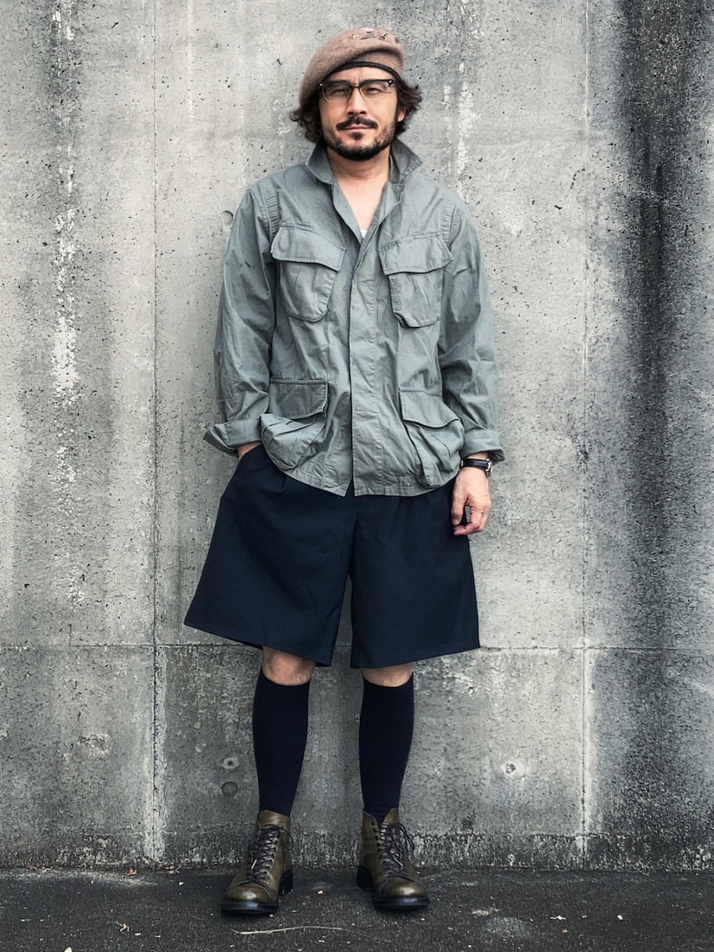 グリーン系のミリタリージャケット、ブルー系のスラックス、グリーン系のブーツを着用したメンズの秋コーディネートの3枚目の写真