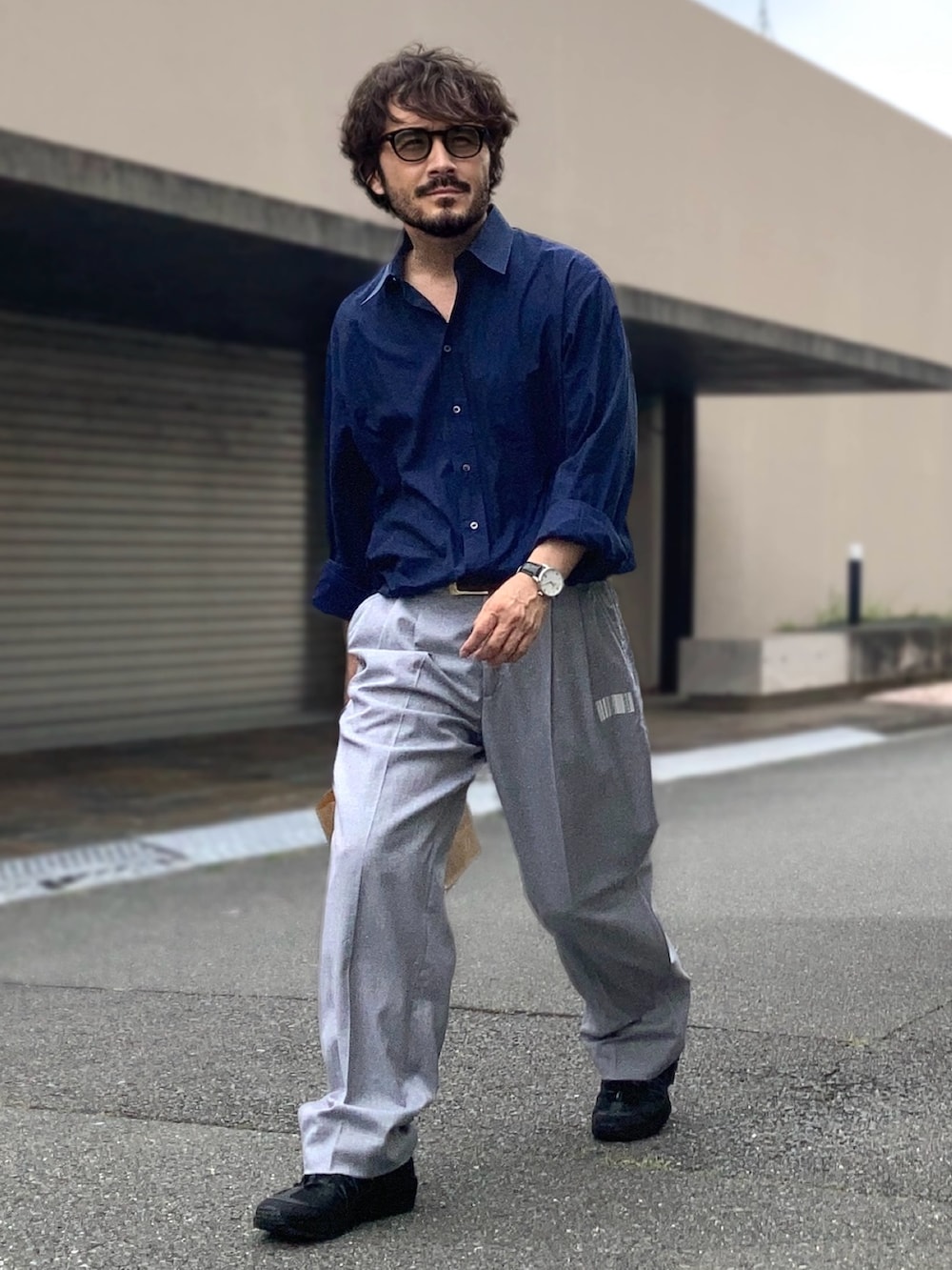 ブルー系のシャツ/ブラウス、グレー系のスラックス、ブラック系のスニーカーを着用したメンズの夏コーディネートの2枚目の写真