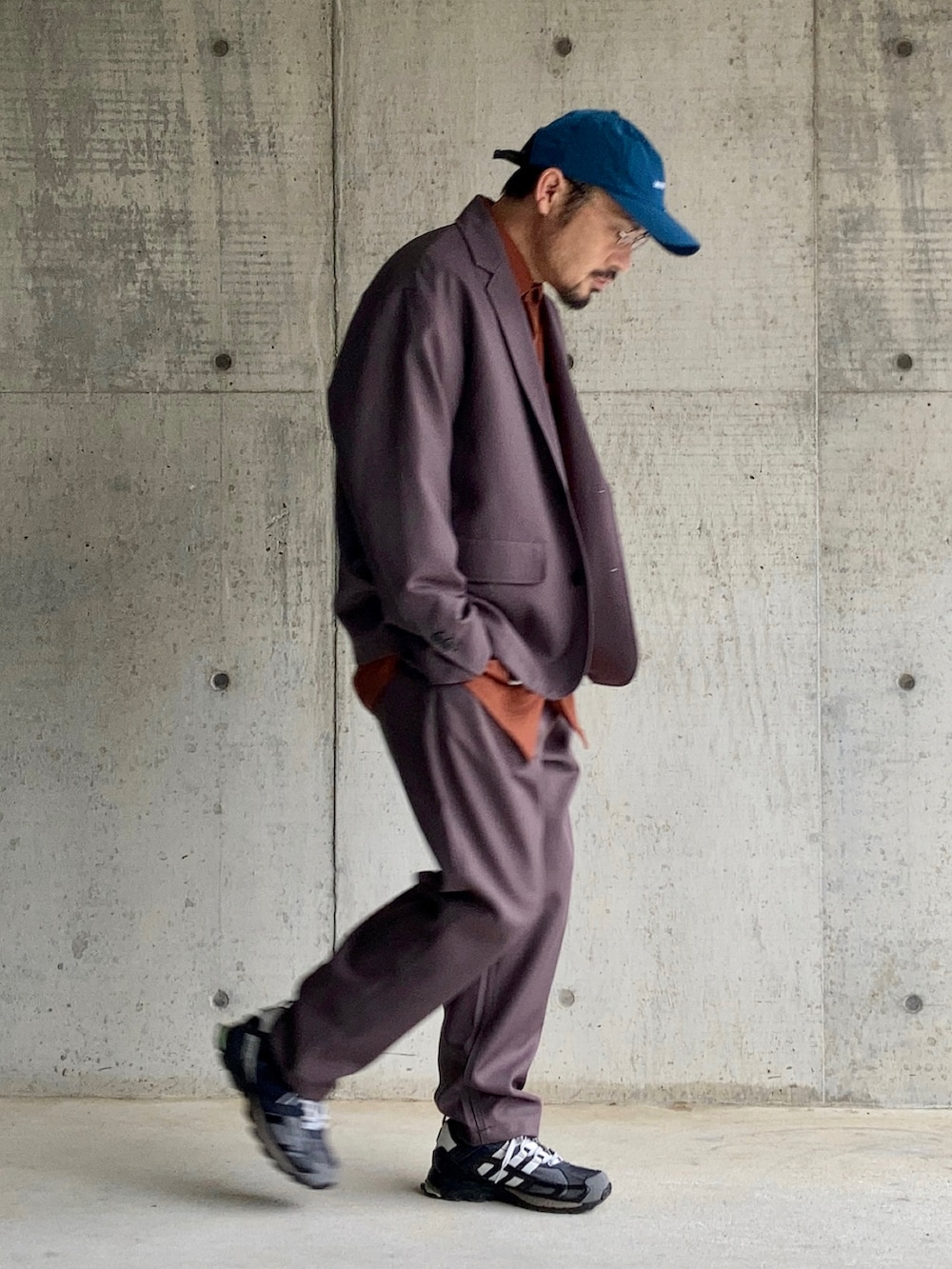 オレンジ系のシャツ/ブラウス、グレー系のセットアップ、ブラック系のスニーカーを着用したメンズの春コーディネートの4枚目の写真