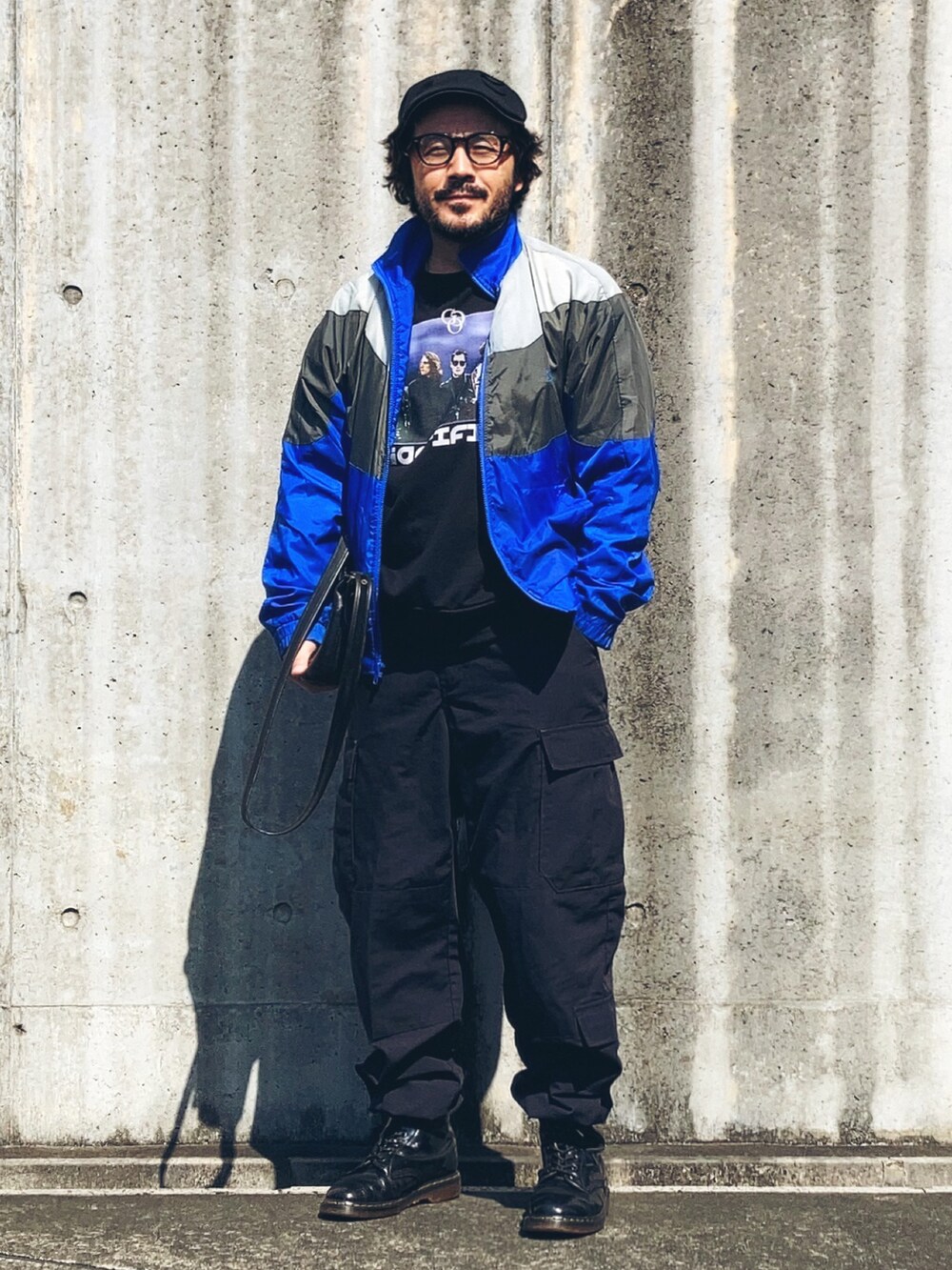 ブラック系のスウェット、ブルー系のナイロンジャケット、ブラック系のカーゴパンツを着用したメンズの春コーディネートの2枚目の写真