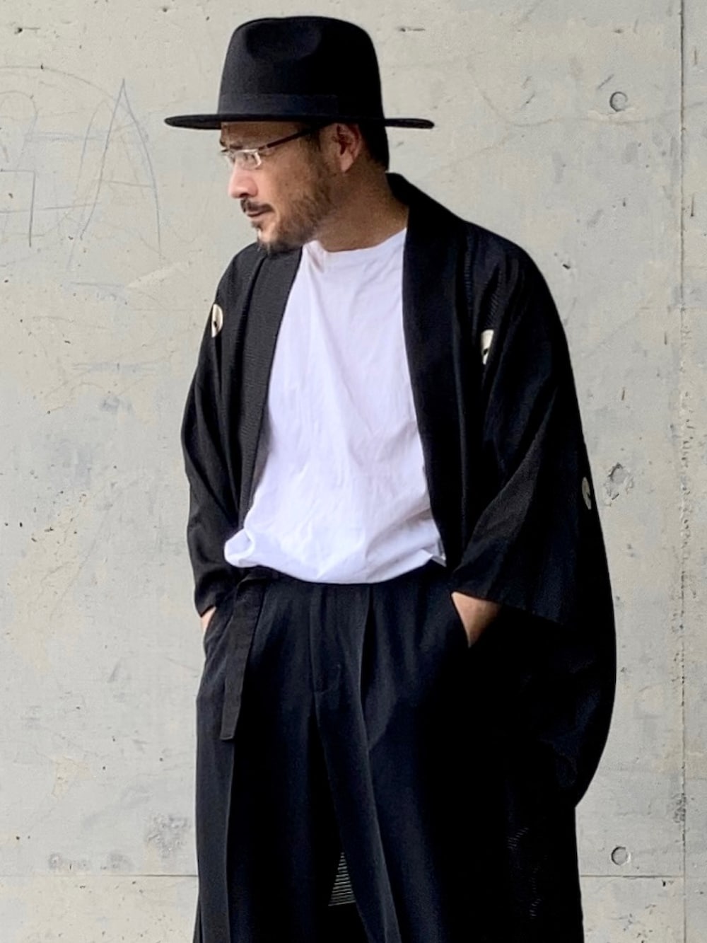 ホワイト系のTシャツ/カットソー、ブラック系のスラックス、ブラック系のサンダルを着用したメンズの夏コーディネートの5枚目の写真