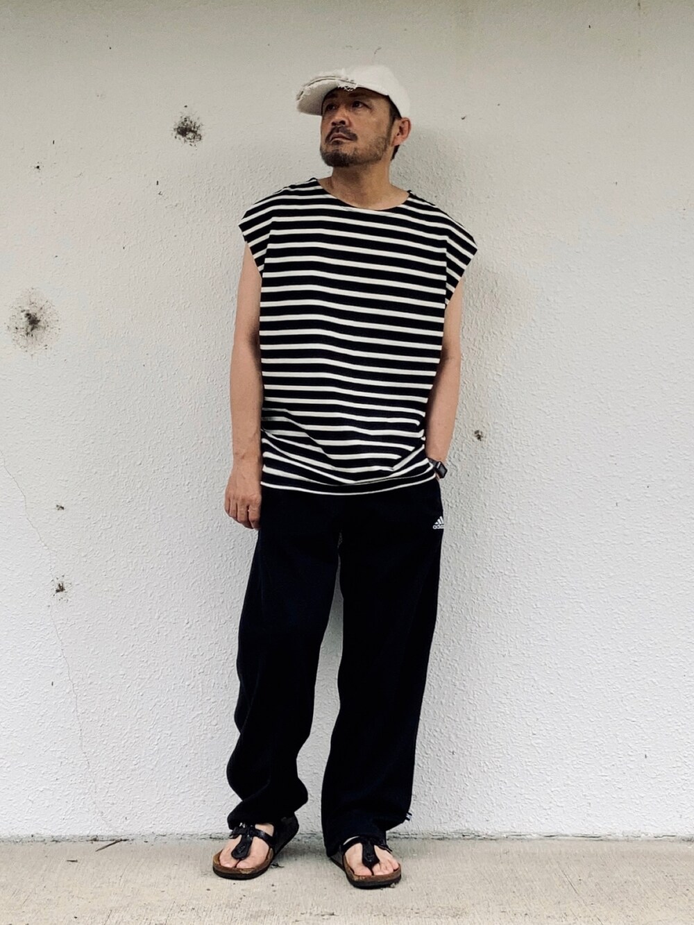 ブラック系のTシャツ/カットソー、ブラック系のパンツ、ブラック系のサンダルを着用したメンズの夏コーディネートの2枚目の写真